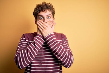 Kıvırcık saçlı, sıradan çizgili süveter giyen genç, sarışın yakışıklı bir adam ağzını yanlışlıkla ellerle kapatarak şok etti. Gizli konsept.
