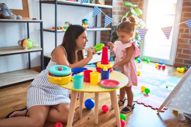 Genç, güzel öğretmen ve bebek, anaokulundaki masada halkalar kullanarak piramit inşa ediyorlar.