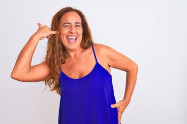 Orta yaşlı olgun bir kadın, izole edilmiş beyaz arka planda durup gülümsüyor, telefonla el ve parmak hareketleri yapıyor, telefonda konuşuyor gibi. İletişim kavramları.