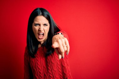 Young brunette woman with blue eyes wearing casual sweater over isolated red background pointing displeased and frustrated to the camera, angry and furious with you