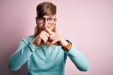Pembe arka planda gözlük takan yakışıklı kızıl saçlı yakışıklı. Reddedilme yüz ifadesi olumsuz işaret veriyor.