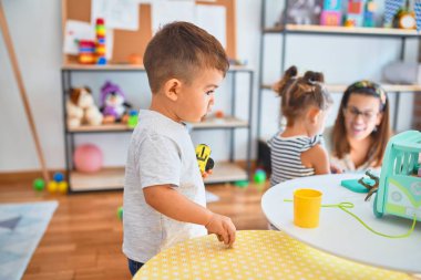 Güzel öğretmen ve bir grup çocuk anaokulunda bir sürü oyuncakla oynuyorlar.