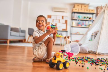 Güzel Afrikalı Amerikalı çocuk anaokulunda gülümseyen küçük yapı taşlarıyla oynuyor.