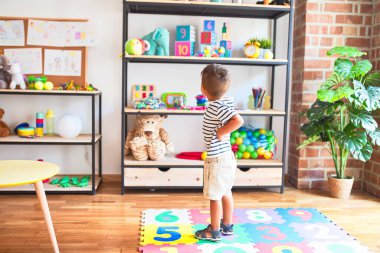 Anaokulunda bir sürü oyuncakla bekleyen güzel bir çocuk.