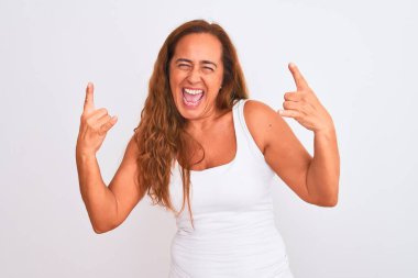 Middle age mature woman standing over white isolated background shouting with crazy expression doing rock symbol with hands up. Music star. Heavy music concept.