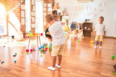 Anaokulunda bir sürü oyuncağın etrafında maymun maskesi takan sevimli sarışın ikizler.