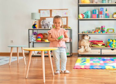 Anaokulunda plastik kurbağalarla oynayan güzel sarışın kız.
