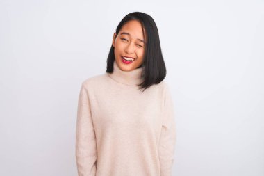 Young chinese woman wearing turtleneck sweater standing over isolated white background winking looking at the camera with sexy expression, cheerful and happy face.