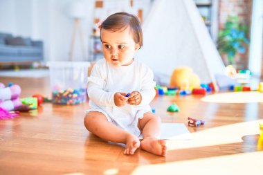 Anaokulunda renkli oyuncaklar arasında mutlu güzel bir bebek.