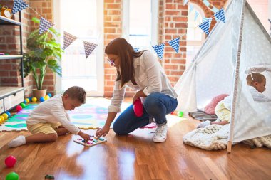 Güzel öğretmen ve çocuk matematik öğreniyor. Anaokulunda bir sürü oyuncağın etrafında sayılar bulmaca oyunu oynuyor.