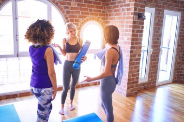 Mutlu gülümseyen genç ve güzel bir sporcu grubu. Beden dersinde yoga dersinden önce ayakta konuşma.