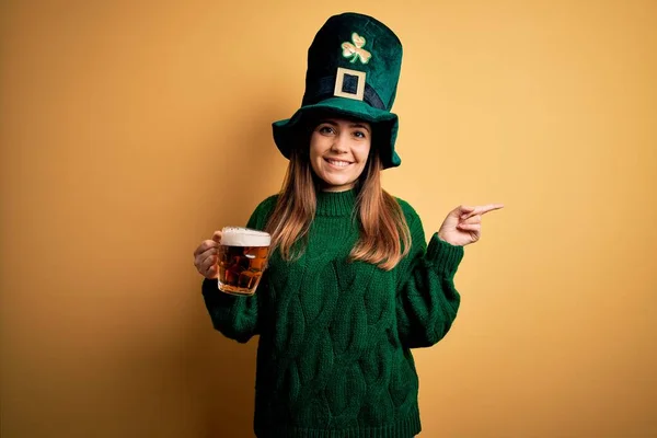 若い美しい女性を身に着けている緑の帽子を飲んで瓶のビール聖人の日のお祝い非常に幸せなポインティングで手と指で側面 — ストック写真