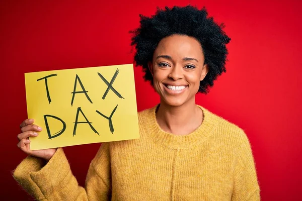年轻的非洲裔美国女人 卷曲的头发 手中拿着印有税日信息的纸 脸上挂着快乐的表情 脸上挂着自信的微笑 露出牙齿 — 图库照片