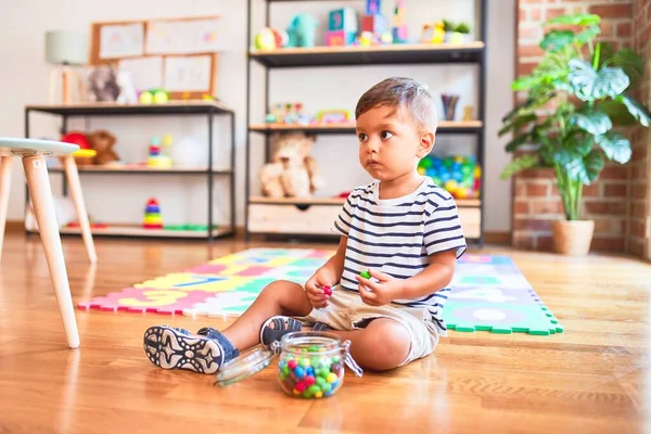 Mooie Peuter Jongen Zitten Puzzel Eten Van Kleine Gekleurde Chocolade — Stockfoto