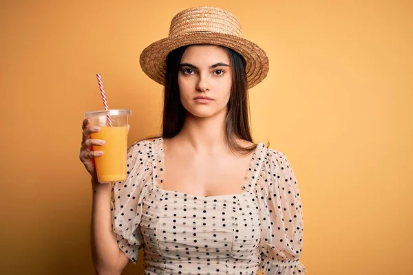 若いです美しいですブルネット女性オン休暇身に着けています夏の帽子飲むオレンジジュースとともに自信を持って式上のスマート顔考え深刻な — ストック写真