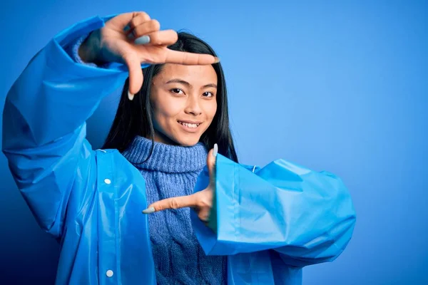 Jonge Mooie Chinese Vrouw Dragen Regenjas Staan Geïsoleerde Blauwe Achtergrond — Stockfoto
