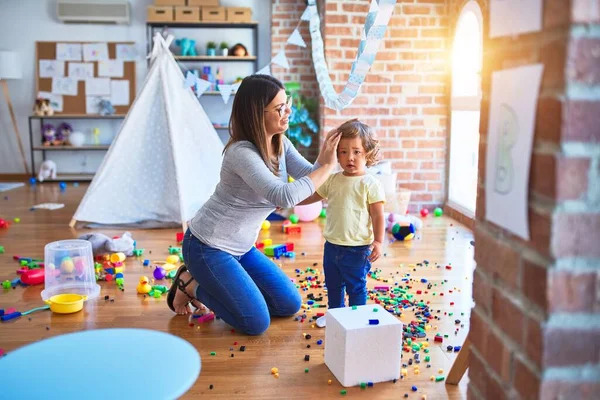 Anaokulunda oynayan genç ve güzel öğretmen ve bebek.