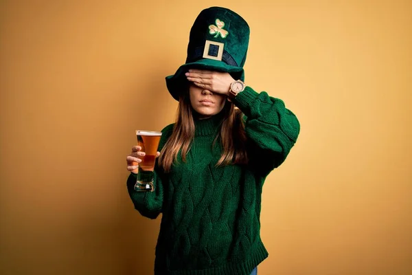 年轻美丽的女人戴着绿色的帽子 在圣徒帕里克的日子里喝着一杯啤酒 用手捂着眼睛 神情严肃而忧郁 目光短浅 躲藏和拒绝的概念 — 图库照片
