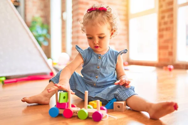 漂亮的高加索婴儿在五颜六色的游戏室玩玩具 幼稚园带木制火车的快乐和玩乐 — 图库照片