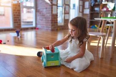 Anaokulunda oyuncak oyuncaklarıyla oynayan sevimli sarışın çocuk.