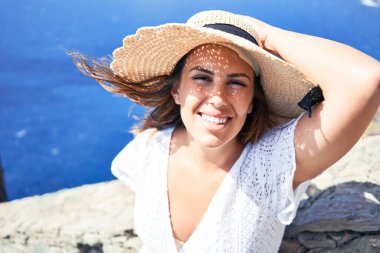 Genç ve güzel bir kadın dağ manzarasında yaz tatilinin tadını çıkarıyor. Gezgin kız okyanus manzarasıyla mutlu gülümsüyor.