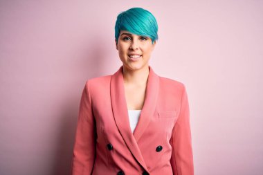 Young beautiful businesswoman with blue fashion hair wearing jacket over pink background with a happy and cool smile on face. Lucky person.