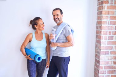 Orta yaşlı güzel sporcu çift mutlu gülümsüyor. Yüzünde gülümsemeyle spor salonunda kameraya bakarken.