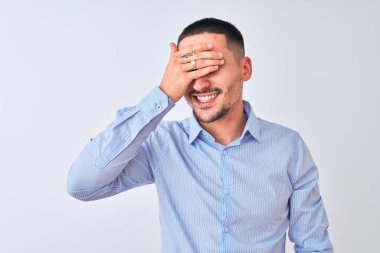 Genç yakışıklı iş adamı izole edilmiş arka planda duruyor. Gülümsüyor ve gülümsüyor. Gözlerini şaşkınlıkla kapatıyor. Kör kavram.