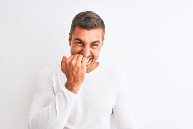 İzole edilmiş arka planda beyaz gömlek giyen yakışıklı bir genç. Ağzı tırnak ısıran elleri yüzünden gergin ve stresli görünüyor. Endişe sorunu.