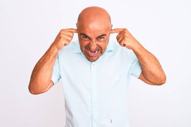 Orta yaşlı yakışıklı bir adam, izole edilmiş beyaz arka planda dikilmiş yüksek sesli müzik sesi için rahatsız edici ifadeleri olan parmaklarıyla kulaklarını kapatıyor. Sağır kavramı.