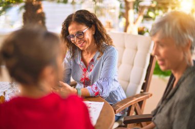 Orta yaşlı kadınlarla buluşup, öğle yemeği yiyip, kahve içiyorlar. Olgun arkadaşlar mutlu bir şekilde gülümsüyor. Güneşli bir günde evde akıllı telefon kullanıyorlar.