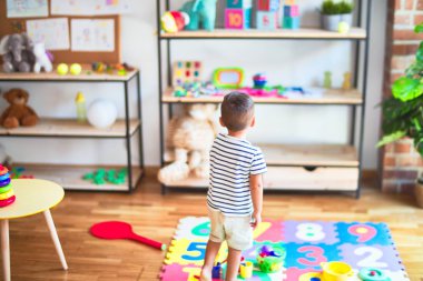 Anaokulunda bir sürü oyuncakla bekleyen güzel bir çocuk.