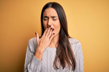 Sarı arka planda beyaz süveter giyen genç, güzel esmer kadın ağzıyla esnemekten sıkılmış. Huzursuz ve uykulu..