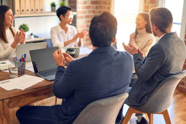 Group of business workers smiling happy and confident. Working together with smile on face applauding one of them at the office
