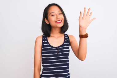 Young chinese woman wearing striped t-shirt standing over isolated white background showing and pointing up with fingers number five while smiling confident and happy.