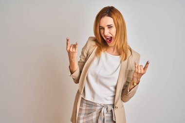 Kızıl saçlı beyaz iş kadını izole edilmiş arka planda duruyor çılgın bir ifadeyle elleri havada rock sembolü yapıyor diye bağırıyor. Müzik yıldızı. Ağır konsept.