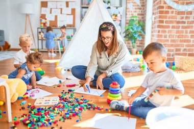 Güzel öğretmen ve bir grup çocuk anaokulunda bir sürü oyuncakla oynuyorlar.