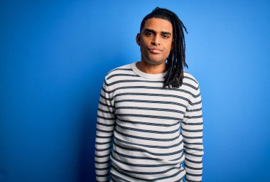 Young handsome african american afro man with dreadlocks wearing casual striped sweater looking sleepy and tired, exhausted for fatigue and hangover, lazy eyes in the morning.