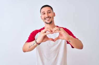 Soyutlanmış arka planda duran yakışıklı genç bir adam. Sevgiyle gülümsüyor. Elleriyle kalp sembolü ve şekli gösteriyor. Romantik konsept.