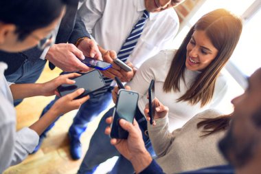 Ofiste el ele duran bir grup iş adamı akıllı telefonları kullanarak semboller yapıyor.