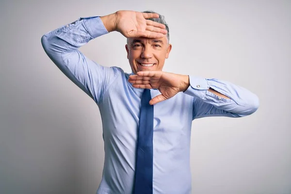 Middle age handsome grey-haired business man wearing elegant shirt and tie Smiling cheerful playing peek a boo with hands showing face. Surprised and exited