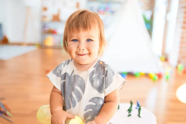 幼稚园里 可爱的幼儿笑着站在那里 手里拿着奶瓶围着许多玩具 — 图库照片