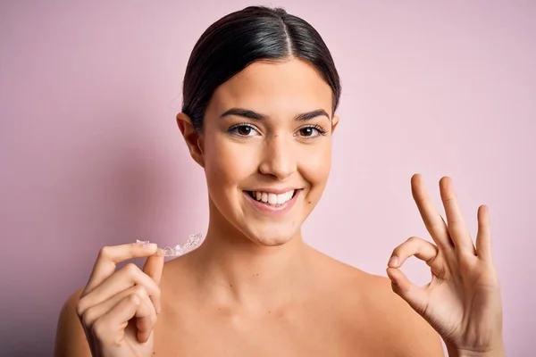 Menina Bonita Jovem Segurando Aligner Dental Sobre Fundo Rosa Isolado — Fotografia de Stock