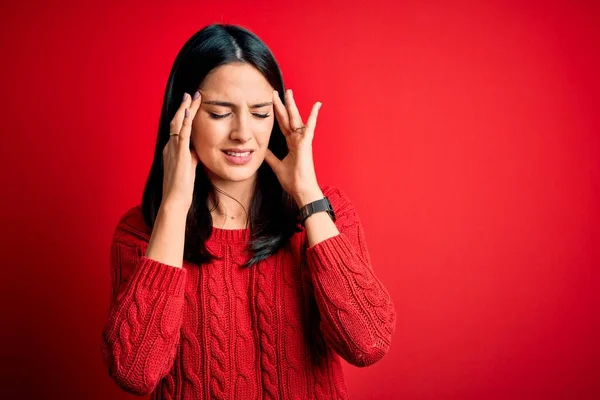 ストレスのために頭痛の種に手で隔離された赤の背景にカジュアルなセーターを着て青い目を持つ若いブルネットの女性 片頭痛に苦しむ — ストック写真