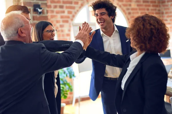 Group of business workers smiling happy and confident. Standing on a circle with smile on face and hands together highing five at the office.