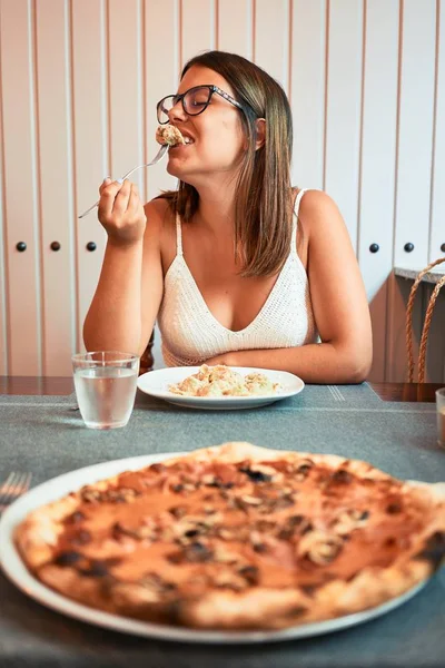 年轻美丽的女人坐在餐厅里享受暑假吃意大利面 — 图库照片