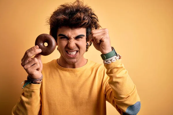 Jovem Homem Bonito Segurando Donut Chocolate Sobre Fundo Amarelo Isolado — Fotografia de Stock