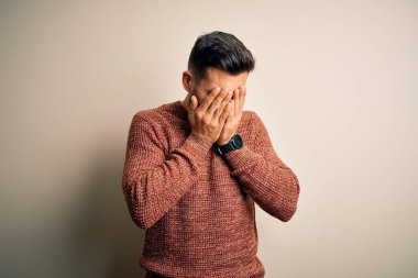 İzole edilmiş beyaz arka plan üzerinde duran sıradan süveter giyen genç yakışıklı bir adam. Ağlarken suratını ellerle kapatan üzgün bir ifade. Depresyon kavramı.