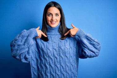 Mavi gözlü, balıkçı yaka kazak giyen, kendine güvenen, gülümseyen, kendini gururlu ve mutlu gösteren genç esmer kadın..