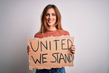 Young beautiful activist woman asking for change holding banner with united stand message scared in shock with a surprise face, afraid and excited with fear expression